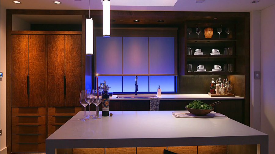 A luxurious kitchen illuminated by different layers and colors of smart lighting.