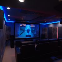 A luxury home theater with blue lighting and the movie “Despicable Me” on screen.