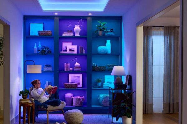 Person reading in a cozy room with shelves lit in blue and purple lighting